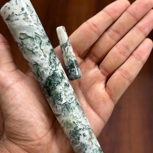 Puede incluir: Dos piezas de piedra tallada, una cilíndrica y otra cónica, con un patrón de blanco, verde y gris. La pieza más grande es cilíndrica, la más pequeña es cónica. La piedra tiene un aspecto natural y orgánico.