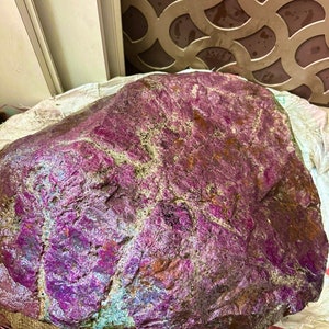 Könnte beinhalten: Ein großer, rauer, violetter und grüner Stein mit einer strukturierten Oberfläche.