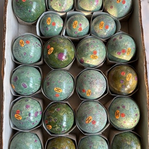 Peut inclure: Une boîte remplie de 20 sphères de pierres précieuses vertes et roses. Chaque sphère porte une étiquette indiquant "Fabriqué en Inde".