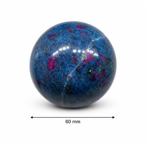 May include: A polished spherical stone featuring a deep blue base with embedded magenta and dark green mineral inclusions. A thin white vein runs across the surface. A measurement indicator below the sphere shows a diameter of 60 mm.