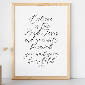 May include: A framed print with a white background and black text. The text reads "Believe in the Lord Jesus, and you will be saved. You and your household. Acts 16:31".