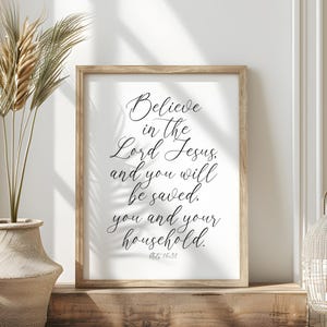May include: A framed print with a white background and black text. The text reads "Believe in the Lord Jesus, and you will be saved. You and your household. Acts 16:31".