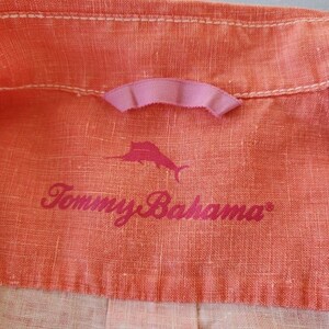 May include: A close-up of a coral-coloured linen fabric with a pink ribbon and the text "Tommy Bahama" in pink lettering. A stylised marlin fish is also printed on the fabric.