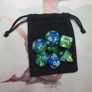 May include: A set of seven green and blue dice with white numbers. The dice are in a black velvet drawstring bag.