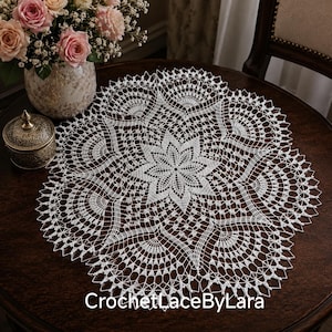 Op de afbeelding: Een rond wit gehaakt kleedje met een centraal sterpatroon, ingewikkelde waaiervormige motieven en een delicate geschulpte rand. De tekst "CrochetLaceByLara" is in het wit onderaan de afbeelding gedrukt.