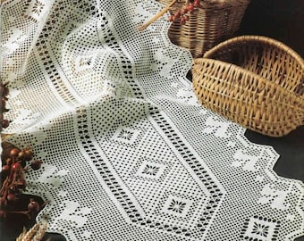 Könnte beinhalten: Weißer gehäkelter Tischläufer mit einem zarten Blumenmuster. Der Läufer liegt über einem Weidenkorb und einem geflochtenen Tablett.