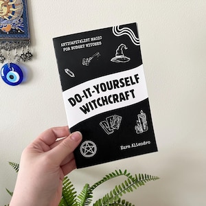 May include: A black and white book titled "Do-It-Yourself Witchcraft" with the subtitle "Anticapitalist Magic for Budget Witches." The cover features illustrations of a witch's hat, cards, a candle, and a pentagram.
