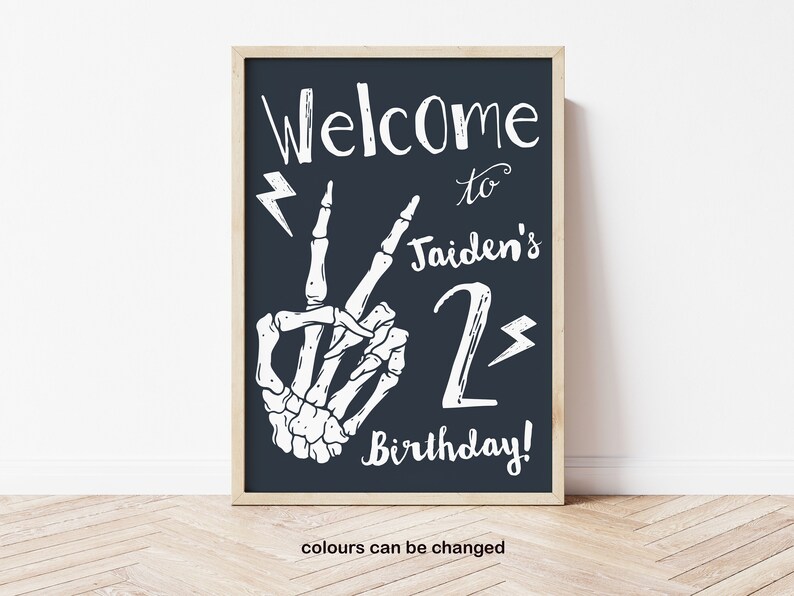 Puede incluir: Un cartel imprimible en blanco y negro con una mano de esqueleto haciendo un signo de paz. El cartel dice "Bienvenido a Jaiden's 2nd Birthday!" con rayos en ambos lados del n&uacute;mero 2.