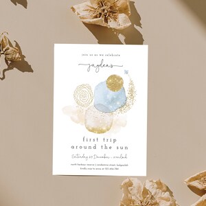 May include: A blue and gold watercolor invitation with the text "Join us as we celebrate Jayden's first trip around the sun. Saturday 23 December - 5:00 pm. North Harbour Reserve | Coronation Street, Balgowlah. Kindly RSVP to Anna at 123 456 7890."
