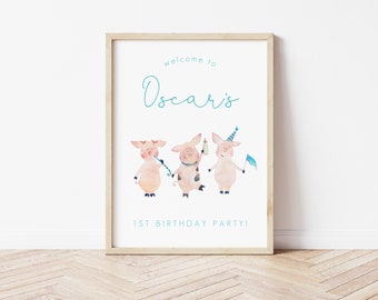 May include: A white printable sign with a light blue border and text that says "Welcome to Oscar's 1st Birthday Party!"  Three watercolor illustrations of pink pigs wearing party hats are in the center of the sign.