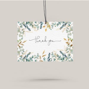 May include: A white card with a watercolour border of green and gold leaves. The card says "Thank you" in black cursive.