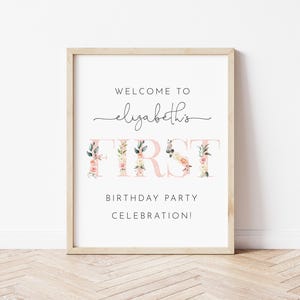 Pu&ograve; includere: Un cartello bianco con cornice in legno, che annuncia "Benvenuti al primo compleanno di Elizabeth!" con accenti floreali rosa.