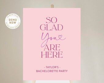 Könnte beinhalten: Rosa Willkommens-Schild mit dem Text "SO GLAD You ARE HERE - TAYLOR'S - BACHELORETTE PARTY" in burgunderfarbener Schrift.