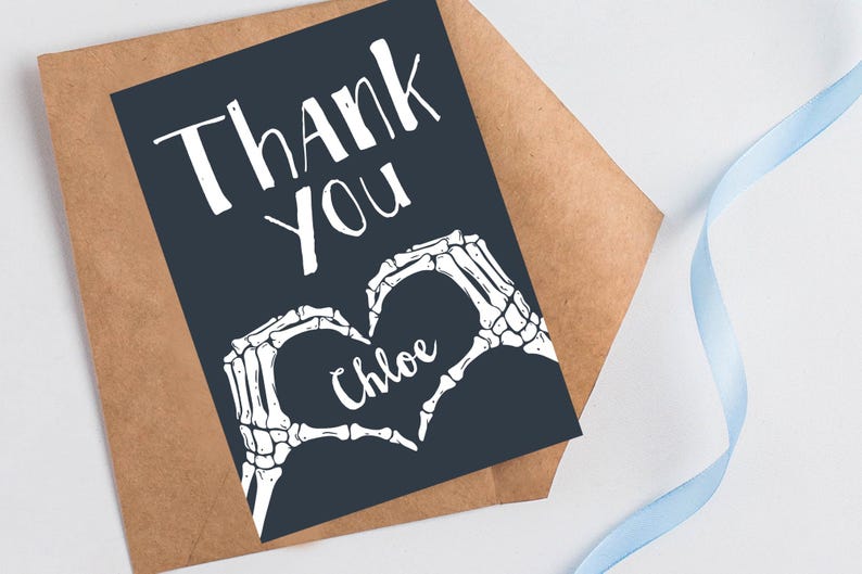 Puede incluir: Una tarjeta de agradecimiento azul oscuro con manos de esqueleto blancas formando un coraz&oacute;n con el nombre "Chloe" en su interior. El texto "Gracias" est&aacute; escrito en blanco en la tarjeta.