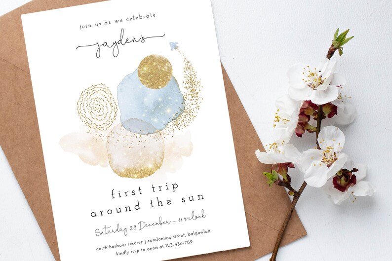 May include: A white invitation card with gold glitter accents and blue watercolor circles. The text reads "Join us as we celebrate Jayden's first trip around the sun. Saturday 29 December - 11 o'clock. North Harbour Reserve | Condamine Street, Balgowlah. Kindly RSVP to Anna at 123-456-789."