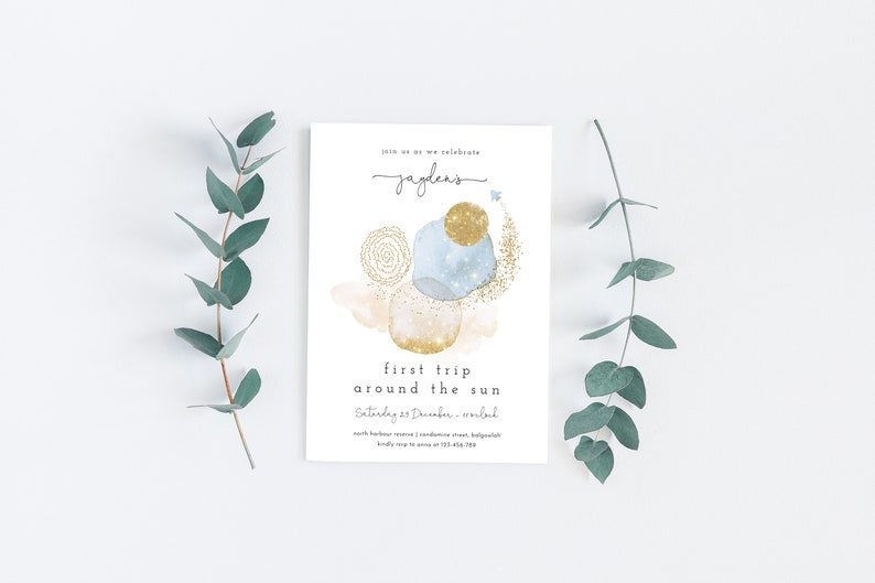 May include: A white invitation card with a blue and gold watercolor design. The text on the card reads "Join us as we celebrate Jayden's first trip around the sun. Saturday 23 December -  [location] North Harbour Avenue, Condamine Street, [location]  RSVP to [phone number] by [date]"