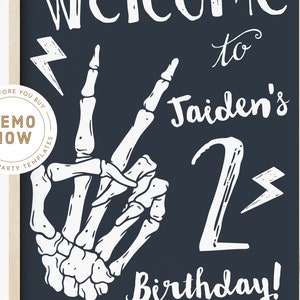 Puede incluir: Un letrero de pizarra azul oscuro con texto blanco que dice "Bienvenido al 2&ordm; cumplea&ntilde;os de Jaiden!" Una mano de esqueleto blanca hace un signo de paz con un rayo encima. Hay otro rayo al lado del n&uacute;mero 2.