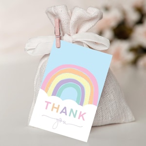 May include: A pastel rainbow with a cloud and the text "THANK you" on a light blue background. This is a thank you tag for a party favor.