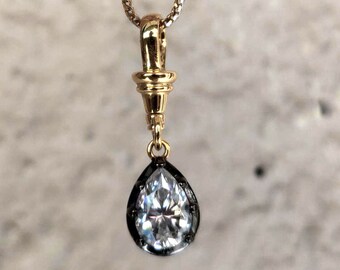 Puede incluir: Un collar de cadena de oro con un colgante en forma de pera con una piedra preciosa transparente.