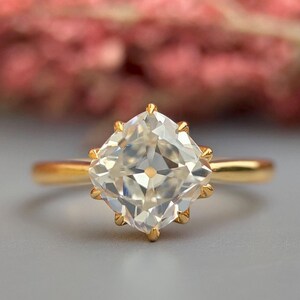 Op de afbeelding: Een gouden ring met een grote, heldere, kussen geslepen edelsteen.