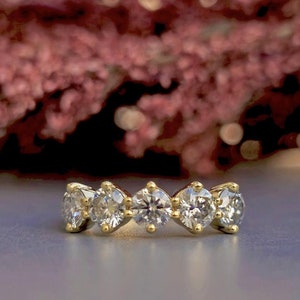 May include: A gold band with five clear, round gemstones set in a row.