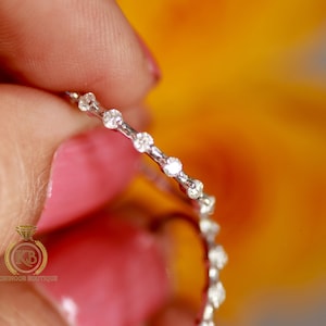 May include: A delicate silver band with a row of small, sparkling diamonds.