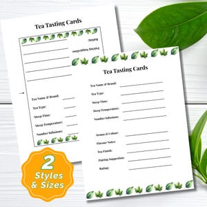 Może przedstawiać: Dwie białe "Tea Tasting Cards" z zielonymi obramowaniami z liści. Karty zawierają sekcje na szczegóły herbaty, aromat, smak i oceny. Żółta i pomarańczowa naklejka głosi "2 Styles & Sizes".
