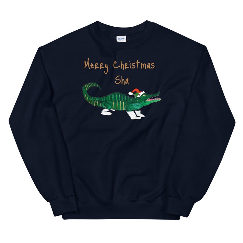 May include: Navy blue sweatshirt with a green alligator wearing a Santa hat. The text "Merry Christmas Sha" is printed on the sweatshirt.