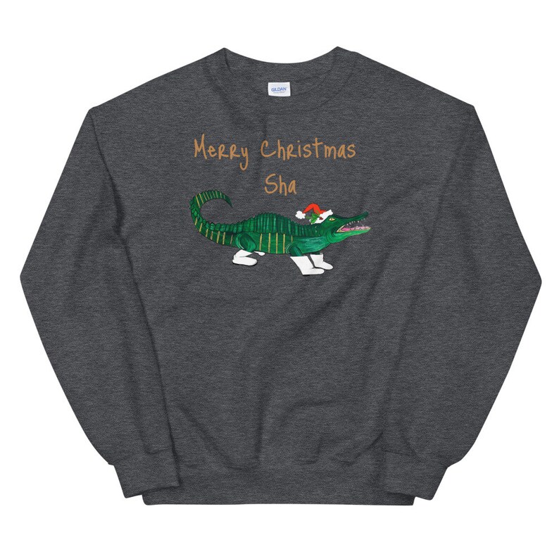 May include: A dark gray sweatshirt with a green alligator wearing a red Santa hat. The text "Merry Christmas Sha" is printed in orange on the front of the sweatshirt.