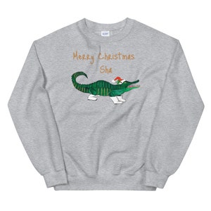 May include: A gray sweatshirt with the text "Merry Christmas Sha" and a green alligator wearing a Santa hat and white boots.