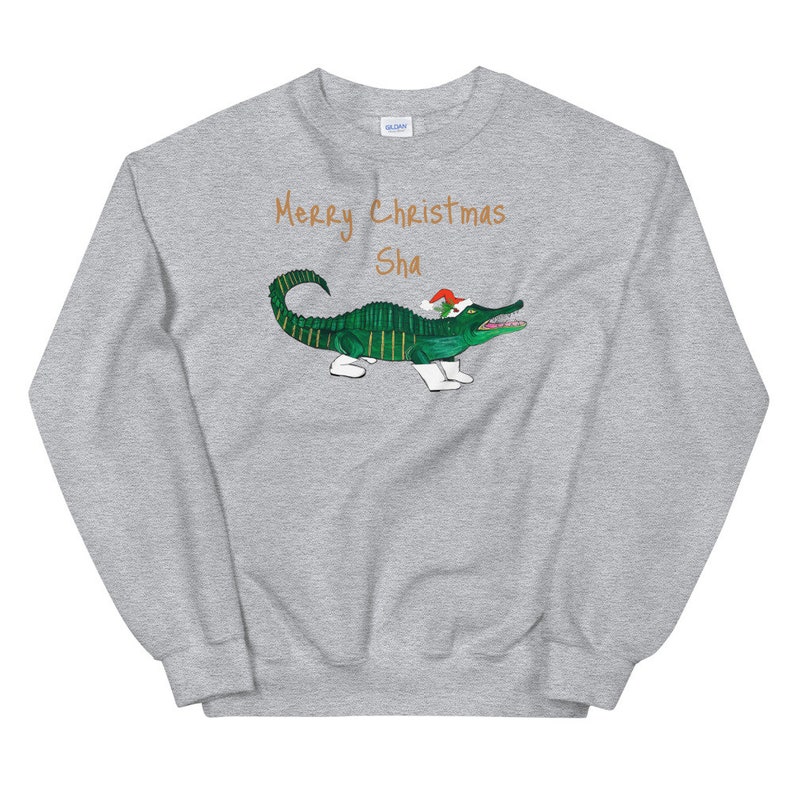 May include: A gray sweatshirt with the text "Merry Christmas Sha" and a green alligator wearing a Santa hat and white boots.