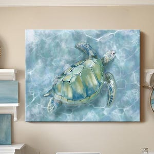 May include: A canvas print of a sea turtle swimming in blue water. The turtle has a green and blue shell. The artwork is displayed above a white desk with a laptop and a wicker chair. Decorative items include shelves with art and woven wall decor.
