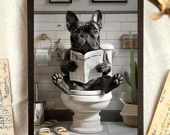 May include: Framed artwork featuring a black French Bulldog sitting on a toilet and reading a newspaper. The dog is the focal point, set against a bathroom backdrop with a toilet, tiles, and a cactus in a woven pot. The frame is dark brown.