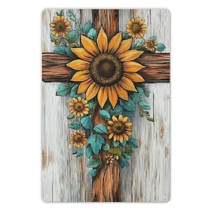 May include: A decorative wooden cross featuring a large sunflower at the center, surrounded by smaller sunflowers and teal leaves. The cross is made of brown wood, set against a white, weathered wood background.