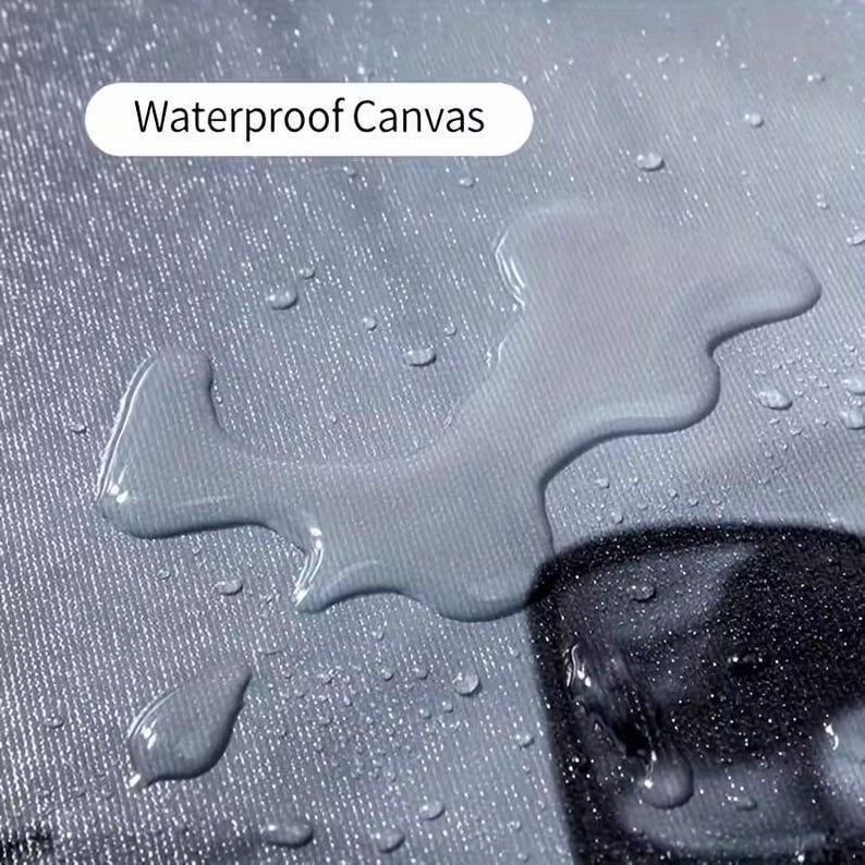 Pu&ograve; includere: Primo piano di un tessuto di tela grigio impermeabile con goccioline d'acqua. Il testo "Waterproof Canvas" &egrave; visualizzato in un rettangolo bianco. La tela sembra essere resistente all'acqua, con acqua che perla sulla superficie.