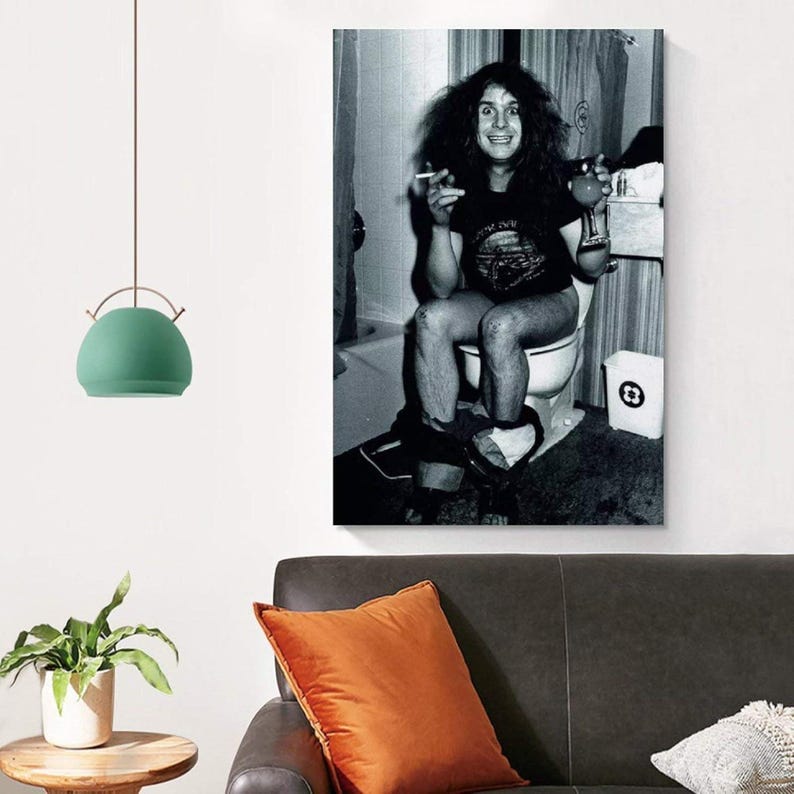 May include: Black and white print of a person sitting on a toilet, holding a cigarette and a drink. The person is wearing a t-shirt and has long, dark hair. The image is a portrait and is displayed on a wall.
