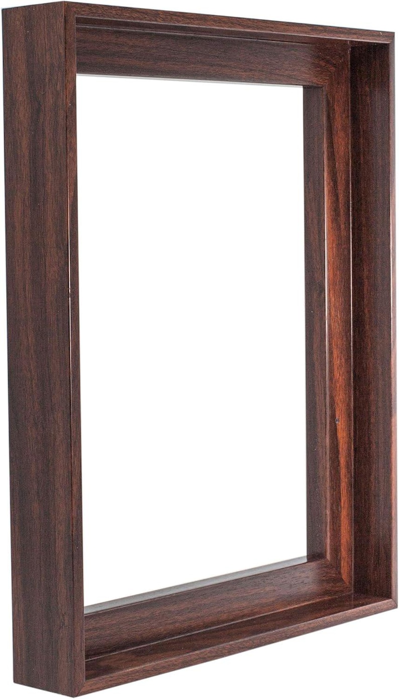 Pu&ograve; includere: Una cornice rettangolare in legno marrone scuro con un profilo profondo. La cornice presenta una ricca texture venata e un bordo interno rientrante, creando un effetto ombra. Progettata per tela o opera d'arte.