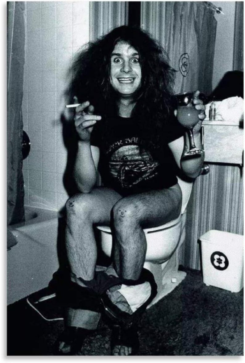 May include: Black and white photograph of a person sitting on a toilet, holding a lit cigarette and a drink. The person is wearing a black t-shirt with a band logo. The image has a vintage, candid feel.