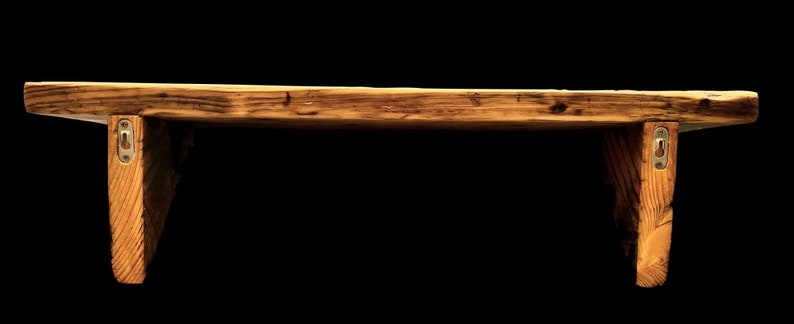 May include: A rustic wooden shelf with a natural wood finish and metal brackets. The shelf is approximately 18 inches long and 6 inches wide.