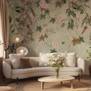 以下が含まれることがあります： 明るい色のソファ、青いアームチェア、丸い木製コーヒーテーブルのある居心地の良いリビングルーム。部屋には花の壁紙、ジュートラグ、ベージュのカーテンがあります。装飾要素には、鳥かごや植物が入った花瓶が含まれます。