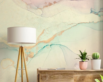 May include: A wooden cabinet with two doors sits in front of a wall with an abstract watercolor design in shades of pink, green, and gold.  There are three potted plants on top of the cabinet.