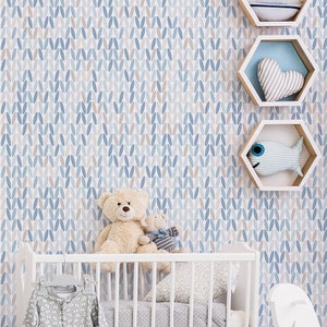 Puede incluir: Una cuna blanca con un dosel a rayas azul y blanco, un caballo de balancín blanco y una silla blanca con un cojín estampado azul y blanco. La habitación está decorada con un tema náutico con papel tapiz azul y blanco y un estante blanco con detalles azules y blancos.
