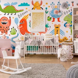 Peut inclure: Un lit bébé blanc avec une guirlande rose et grise suspendue au-dessus. Le lit se trouve dans une chambre d'enfant avec un cheval à bascule blanc, une commode blanche et un berceau à bascule blanc. Les murs sont décorés d'une fresque colorée de monstres avec les mots "BooOOO" et "Roar".