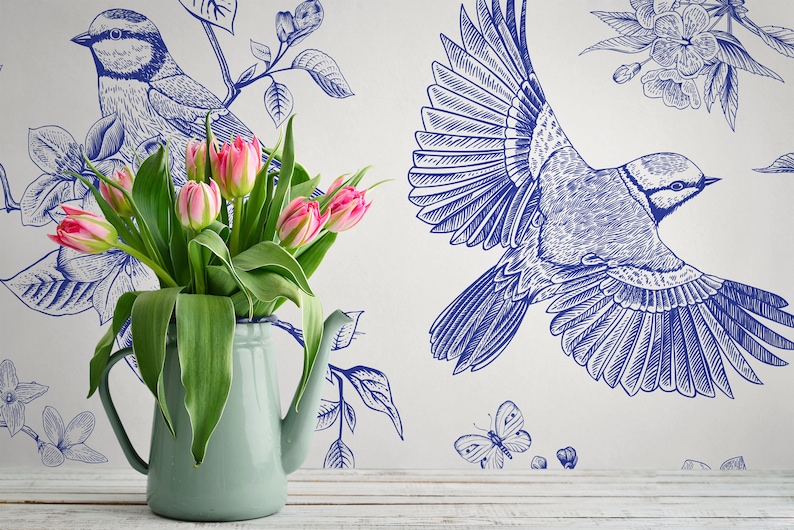 May include: A blue and white floral wallpaper with a bluebird design. A bouquet of pink tulips is in a light blue pitcher in the foreground.