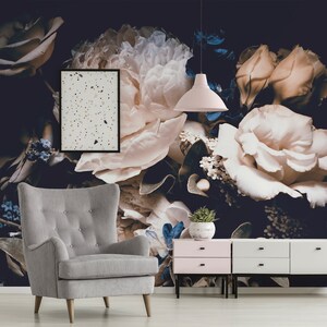 K&ouml;nnte beinhalten: Ein Wohnzimmer-Interieur mit einer floralen Tapete mit gro&szlig;en wei&szlig;en und rosafarbenen Rosen, einem grauen Sessel, einem rosa-wei&szlig;en Beistelltisch und einer wei&szlig;en Lampe, die von der Decke h&auml;ngt.