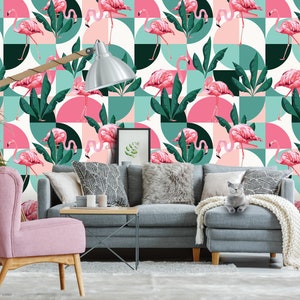 May include: A pink and green geometric wallpaper featuring pink flamingos and tropical leaves. The wallpaper is in a living room setting with a pink armchair, a gray sofa, and a gray cat.