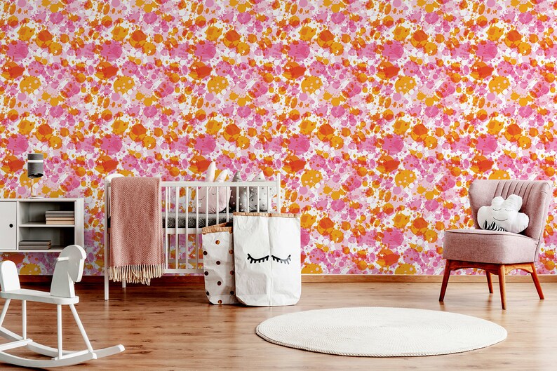 May include: A nursery room with a white crib, a rocking horse, a pink armchair, and a white rug. The walls are covered in a pink and orange splatter paint wallpaper.
