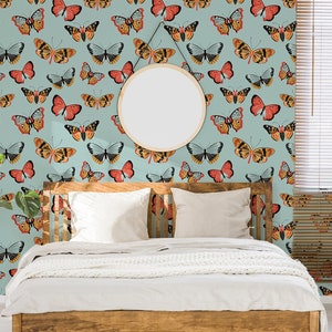 May include: A bedroom with a light blue wall featuring a repeating pattern of colorful butterflies. The wall is decorated with a round mirror. A wooden bed with white bedding is in the center of the room. A potted plant is on the left side of the bed.