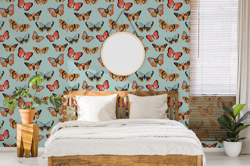 May include: A bedroom with a light blue wall featuring a repeating pattern of colorful butterflies. The wall is decorated with a round mirror. A wooden bed with white bedding is in the center of the room. A potted plant is on the left side of the bed.