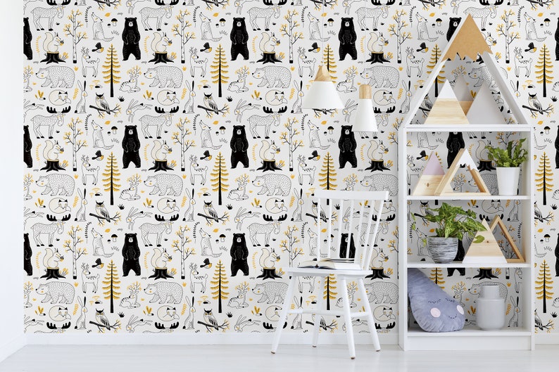 May include: A white wall with a black and gold woodland animal print wallpaper. A white chair and a white bookshelf with wooden shelves and triangular wooden decorations are in front of the wall.